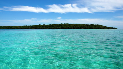 weiter Blick über türkisgrünes Meer zu grüner Insel