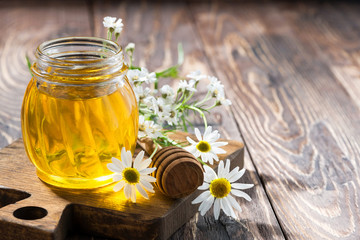 jar with fresh flower honey and dark wooden background