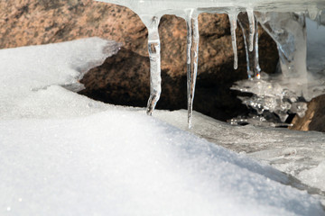 Snow, stones, ice and icicles. Nature background.