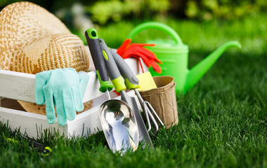 Gardening tools and a straw hat on the grass in the garden.