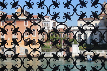 Fototapeta na wymiar The Grand Canal and buildings in Venice, seen through a beautiful wrought iron window grill of a palazzo. In the small red house, Casetta Rossa, lived the poet D’Annunzio. Venice, Italy, Europe.