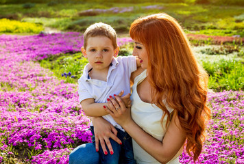 Young mother playing with her little son in the garden. Mother's Day concept