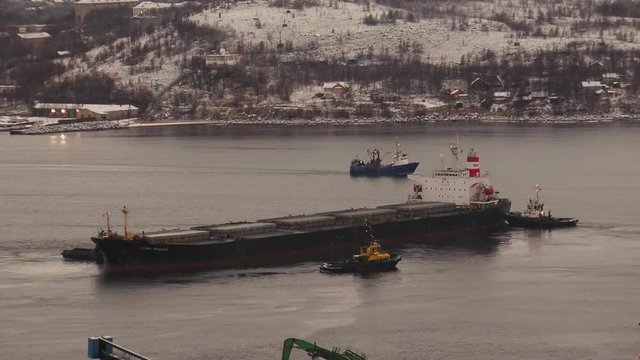 Murmansk, Russia - November 9, 2016: Kola Bay - Three tug deploy large ship. Winter frost. 