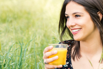 Attractive girl drinking orange juice outdoors.
