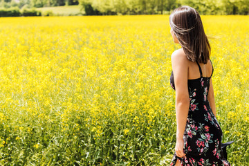 Fototapeta premium Rear view of woman next to yellow flower field.