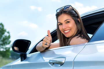Young female car driver doing thumbs up.