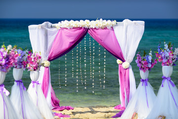 Wedding arch for ceremony is decorated with curtains and flowers
