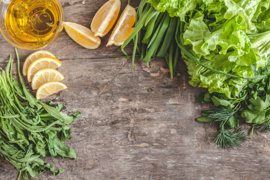 Wooden old background around greens, leaves, lettuce, lemon, oli