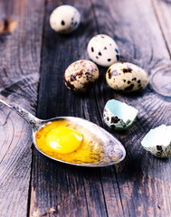Egg quail with yolk in an iron spoon