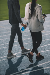 Two young sportswomen walking together on running track stadium