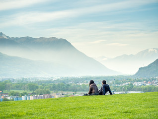 Fototapeta na wymiar Two people sit on green grass