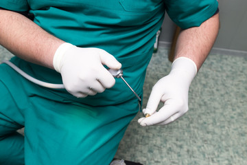 A dentist prepares an implant in the clinic