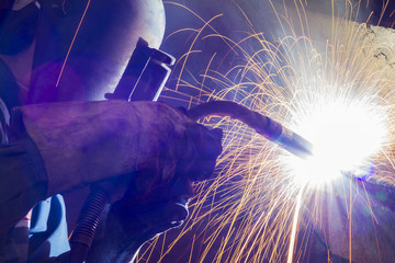 Worker welding steel by MIG/MAG weld (Argon welding) in industrial factory. - obrazy, fototapety, plakaty