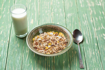 Bowl of oat flakes and glass of milk, on wooden background.