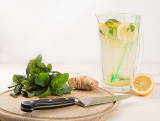 A glass decanter with a summer refreshing lemonade made of lemons and ginger with mint added on a...