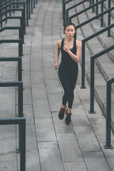 Young fitness woman in sportswear running on stadium stairs