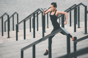 Athletic young woman in sportswear running on stadium stairs