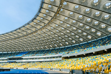 rows of yellow and blue stadium seats on olympic stadium - obrazy, fototapety, plakaty
