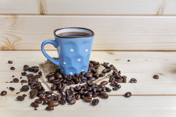blue coffee cup with white dots and coffee beans on a wooden background