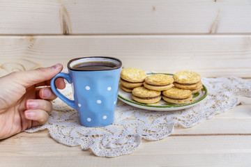 Female hand holding cup of coffee with biscuits 