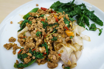 Asian Thai oriental noodle topped with spicy traditional stir fried pork and crispy basil leaves