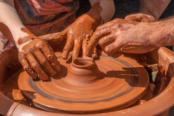 the teacher teaches to sculpt in clay pot on a turning pottery wheel