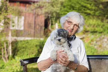 Senior woman hugging her poodle dog in the nature