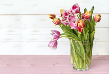 bouquet of pink tulips on a white  wooden background with space for message.