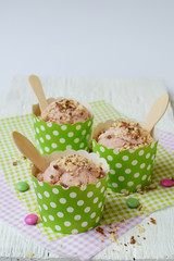 Pink milk ice cream in a paper cup on a white wooden background. Berry sorbet. Place for text