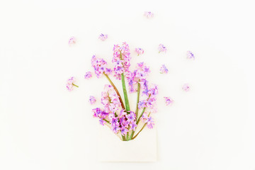 Bouquet of pink hyacinth flowers, petals and paper envelope on white background. Flat lay, top view. Beauty blog concept.