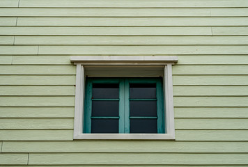 Green windows on old wooden wall