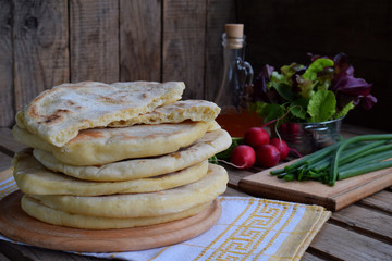Pile of homemade flat bread with lettuce, onion and radish on a wooden background. Mexican flatbread taco. Indian Naan. Space for text