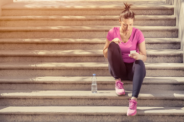 Obraz premium Jogger sitting on stairs and using smartphone 