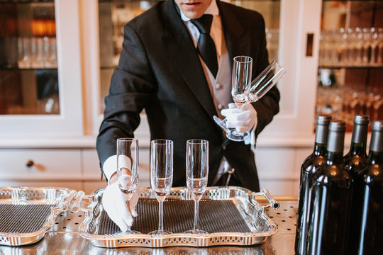 Waiter placing champagne flutes on silver tray 