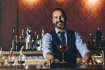 Barman is making cocktail at night club.
