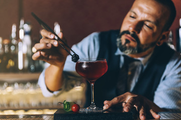 Barman is making cocktail at night club.