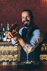 Barman is making cocktail at night club.