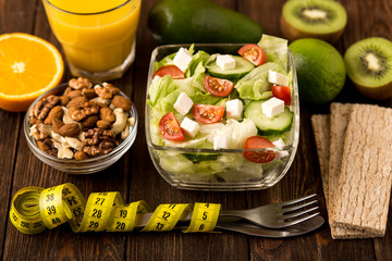 Fresh salad and fruits on wooden background.  Fitness breakfast.  Healthy eating, dieting, slimming and weigh loss concept.