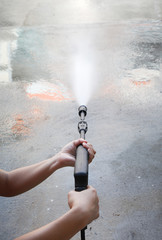 Water hose spray gun washing his cement floor
