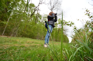 Young blond caucasian girl taking photos on a natural trail