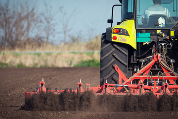 Farmer in tractor preparing land with seedbed cultivator - obrazy, fototapety, plakaty