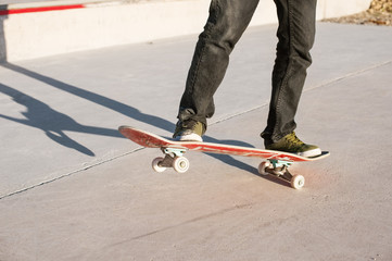 A young guy on a skateboard in a manual on a skatepark on the background of house