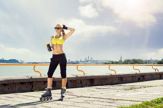 Fit, sporty and athletic young woman. Beautiful girl rollerblading on skates in a sportswear.