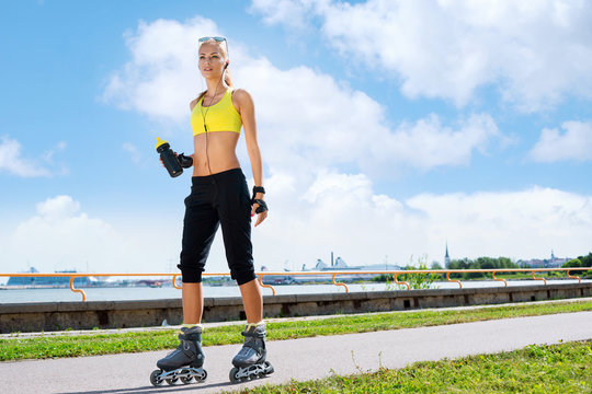 Young, beautiful and fit girl over sky background. Sporty woman rollerblading on skates.