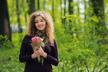 Beautiful red-haired girl in a park with a bouquet of flowers.