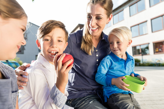 Mutter und Kinder in Schule machen Pause mit Apfel und Brotdose