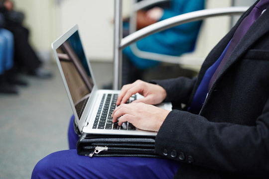 Side view portrait of unrecognizable businessman using laptop computer for work during subway ride