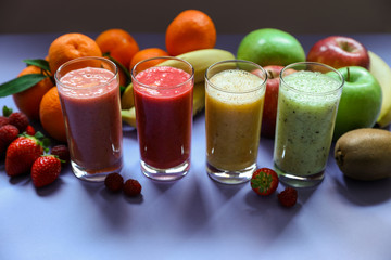 Four different smoothies and ingredients berries, banana, tangerine, kiwi, apple.