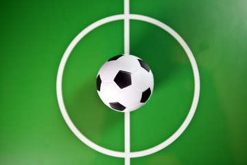 Toy soccerball in a midfield, in the center of the green field