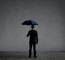 Businessman with umbrella. Dark, dramatic background. Business, protection, insurance, concept.